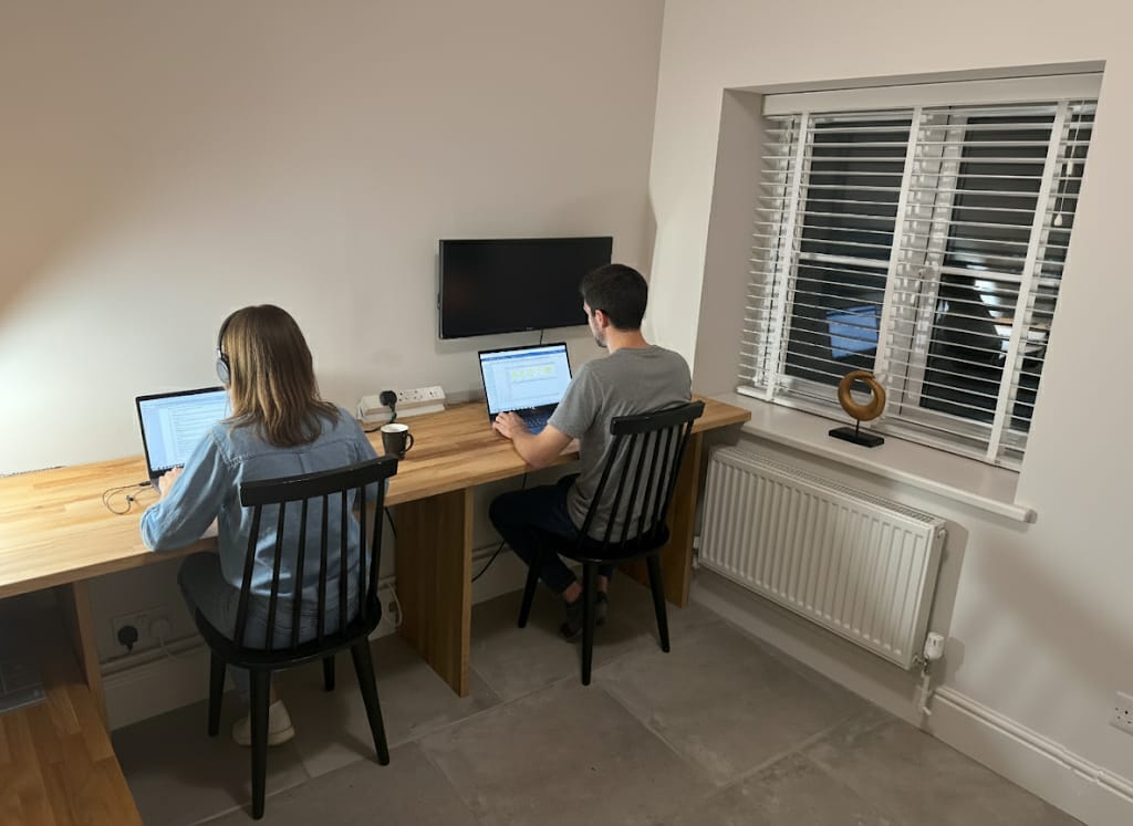 Two colleagues working side by side at the long desk